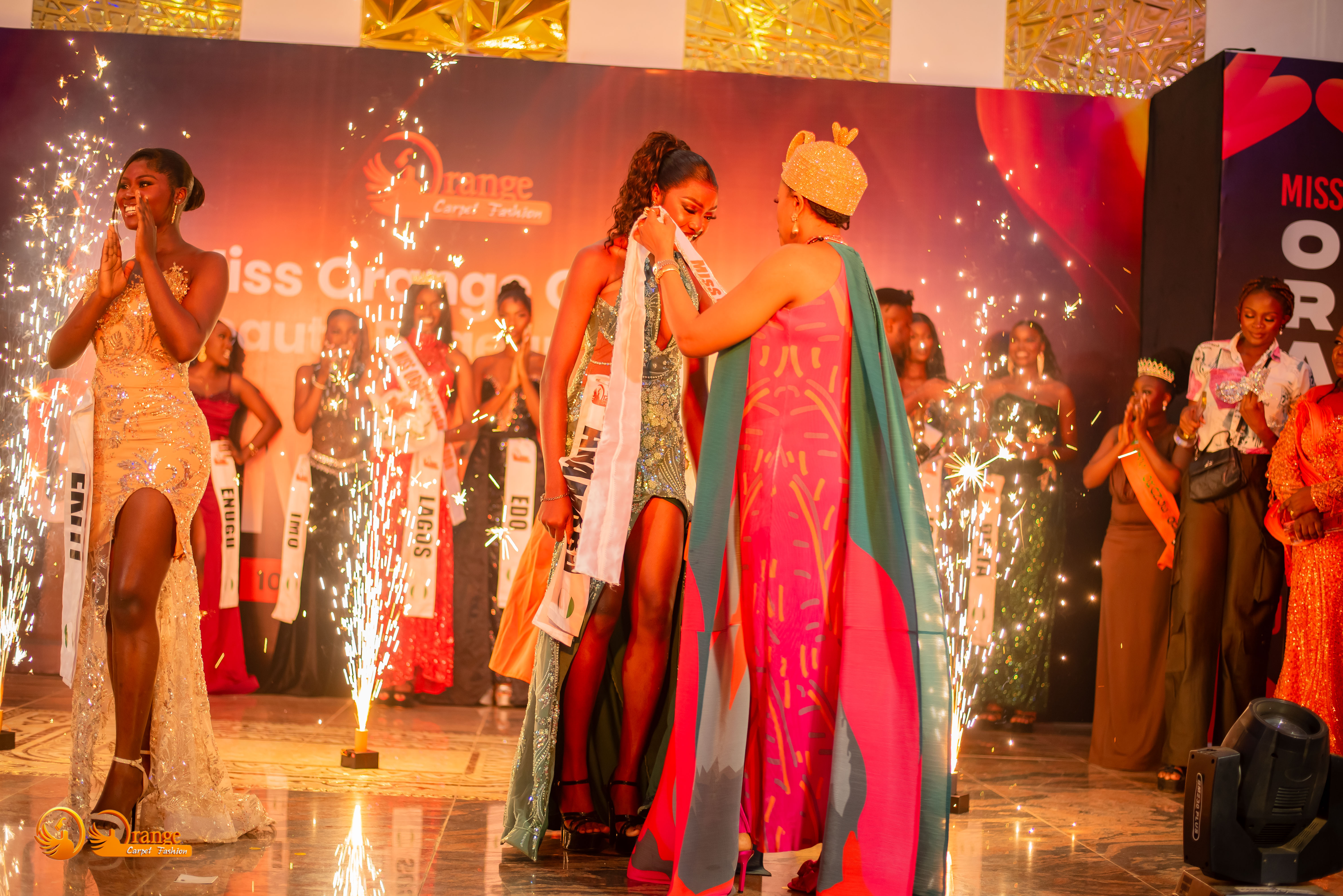 Abigael receiving her sash amid pyrotechnics and cheering contestants